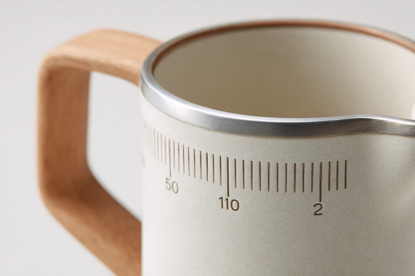 Macro of the graduation lines and numerals inlaid beside the brushed steel rim of a Pourline pitcher